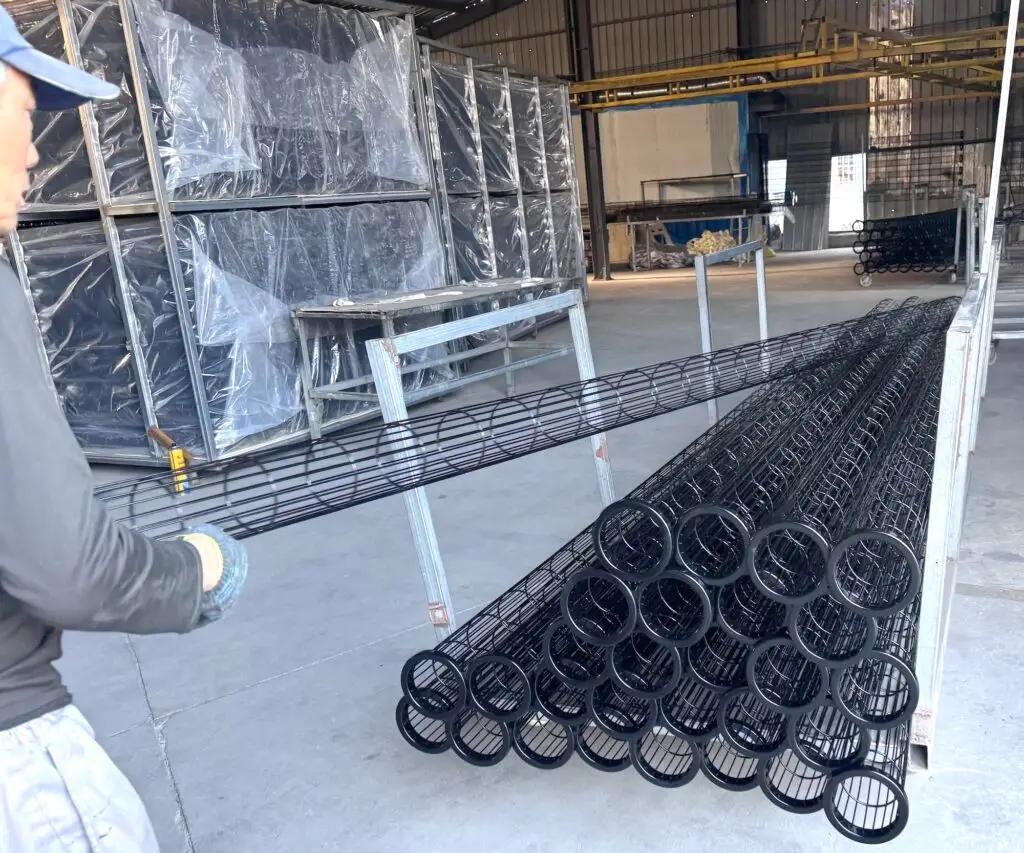 Technician inspecting the silicone-coated surface of a custom filter cage during quality inspection before delivery.